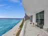 Expansive private balcony featuring glass railings and breathtaking, unobstructed panoramic ocean views.