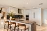Kitchen featuring flat-panel cabinetry, a waterfall-edge stone countertop, integrated stainless steel appliances, a stainless steel range hood, and a 