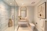 Glass-enclosed shower with horizontal wall tile, floating vanity with a stone countertop, integrated sink, and an arched wall mirror