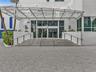 Elegant building entrance featuring a contemporary glass canopy, beautifully paved entryway, and sleek stainless steel railings, creating a sophistica