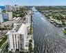 Waterfront high-rise building featuring a multi-story glass facade, dedicated ground-level swimming pool, and direct canal frontage