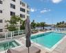 Waterfront pool area featuring a built-in spa, concrete tile decking, and a glass-paneled safety railing