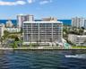 Waterfront multi-story residential building featuring floor-to-ceiling glass balconies, private dockage, a ground-level swimming pool, and manicured l