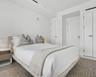 Neutral-toned interior space featuring crisp white walls, recessed ceiling lighting, and multiple floor-to-ceiling closets with minimalist hardware