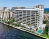 Waterfront mid-rise building featuring extensive private balconies, a ground-level swimming pool, manicured landscaping, and a direct bulkhead seawall