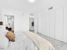 Bright and elegant bedroom featuring dramatic floor-to-ceiling windows, custom built-in wardrobe cabinetry, luxurious marble-look flooring, recessed c