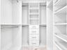 Custom-designed closet featuring ample hanging space, built-in shelving, and a five-drawer storage unit with brushed nickel hardware.