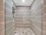 Luxurious spa-inspired shower featuring a frameless glass enclosure, ceiling-mounted rainfall showerhead, handheld shower, and elegant horizontally pa