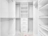 Luxurious custom-designed white closet system featuring generous hanging space, adjustable shelving, and built-in drawers with polished hardware for e