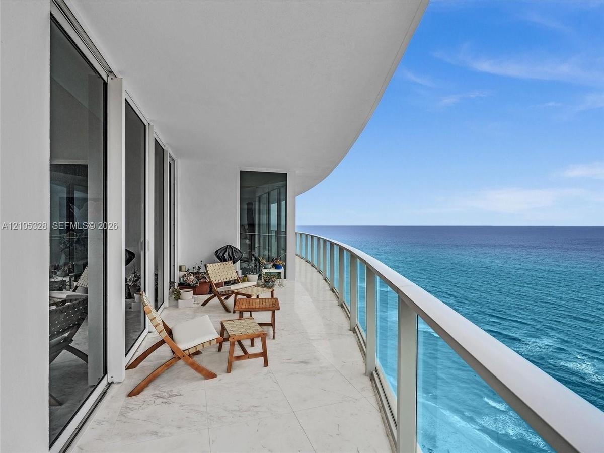 Expansive curved balcony with glass railings and panoramic ocean views.