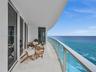 Expansive curved balcony with glass railings and panoramic ocean views.