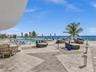 Experience oceanfront resort-style living at Apogee Beach, featuring an inviting swimming pool, expansive pool deck, sleek glass railings, and direct 