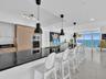 Gourmet kitchen featuring integrated appliances, sleek black countertops, and contemporary pendant lighting.