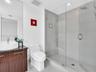 Elegant contemporary bathroom featuring a sleek vanity with warm finish cabinetry and a sophisticated dark countertop.