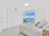 Bright and elegant bedroom featuring dramatic floor-to-ceiling windows, custom built-in wardrobe cabinetry, luxurious marble-look flooring, recessed c