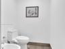 Elegantly appointed private bathroom featuring crisp white walls, warm wood-look flooring, and a modern toilet with an integrated bidet.