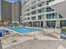 Experience oceanfront resort-style living at Apogee Beach, featuring an inviting swimming pool, expansive pool deck, sleek glass railings, and direct 