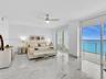 Sliding glass doors opening to a balcony, ceiling fan, white tile flooring, white walls, and a recessed ceiling