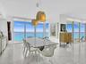 Elegant dining area featuring floor-to-ceiling glass doors and windows, large-format tile flooring, contemporary pendant lighting, and a glass-top din