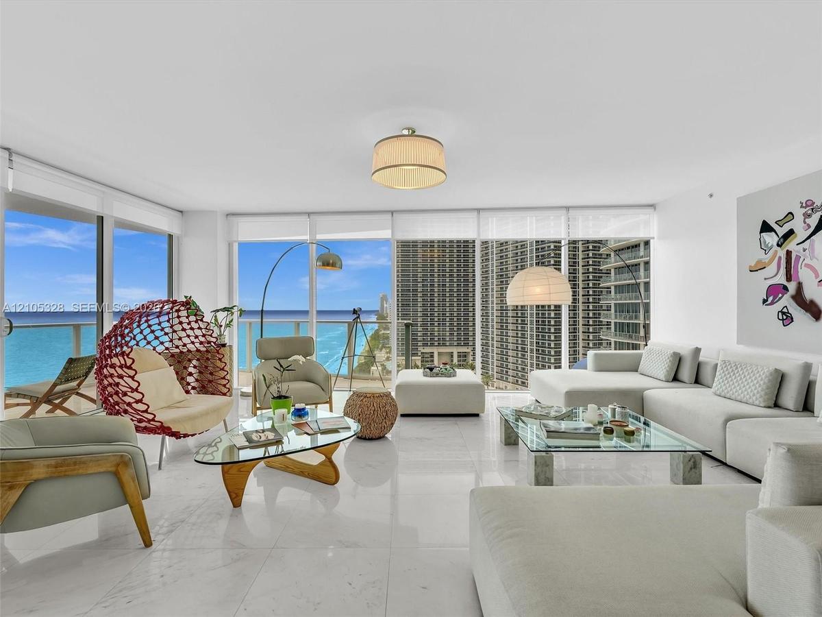 Spacious open-concept living area featuring Carrara marble flooring and recessed ceiling lighting.