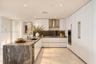 Kitchen featuring flat-panel white cabinetry, stone-patterned countertops, integrated stainless steel appliances, a stainless steel range hood, and ti