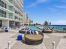 Experience oceanfront resort-style living at Apogee Beach, featuring an inviting swimming pool, expansive pool deck, sleek glass railings, and direct 