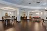 Open-concept interior featuring wood-finish flooring, recessed circular tray ceilings with decorative light fixtures, and a built-in bar with pendant 
