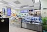 Commercial space featuring wood-plank paneled service counter, stainless steel refrigerated display case, drop ceiling with recessed lighting, and woo