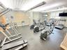 Fitness center featuring textured rubber flooring, panelized drop ceiling, glass block windows, and linear overhead lighting