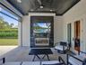 Covered lanai featuring a black shiplap ceiling, recessed lighting, ceiling fan, and a floor-to-ceiling stone fireplace surround with integrated stain