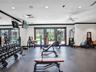 Fitness room featuring wall-to-wall mirrors, recessed lighting, ceiling fan, dark rubber flooring, and multiple glass-paneled exterior doors with dark