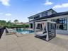 Rear exterior featuring a spacious tiled patio, an in-ground swimming pool, a covered outdoor area, and large black-framed windows