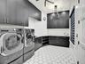 Laundry room featuring floor-to-ceiling matte black cabinetry, contrasting white countertops, geometric hexagonal floor tile, and modern geometric ove