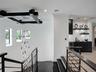 Black metal staircase railing with a multi-pendant glass chandelier, ceiling-mounted geometric accent structure, and a built-in wet bar featuring dark