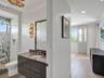 Bathroom featuring a dark-finish floating vanity with a solid-surface countertop, an undermount sink, patterned wall tile within the glass-enclosed sh