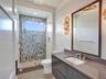 Modern vanity with a dark-toned flat-panel cabinet, solid-surface countertop, and rectangular undermount sink
