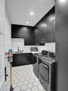 Laundry area featuring full-height matte black cabinetry, contrasting white countertops, an integrated basin with a matte black faucet, and geometric 
