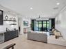 Living area featuring wood-finish flooring, recessed lighting, a ceiling fan, and a built-in wet bar with dark cabinetry and stone countertops
