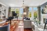 Hardwood-style flooring throughout, built-in shelving, fireplace with stone surround, crown molding, and a crystal chandelier