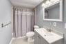 Stylish full bathroom featuring a modern vanity with brushed-nickel fixtures, white framed mirror, and elegant tile backsplash. The space is accented 