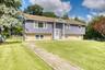 Beautiful split-level home with a welcoming front entrance and manicured lawn. The exterior features a unique combination of soft purple siding and li