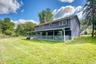 Beautiful outdoor setting showcasing a spacious lawn and a two-story home with a full-length covered porch. The blue exterior contrasts elegantly with