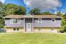 Charming two-story split-level residence showcasing a clean, modern look with purple siding and light brick accents. The symmetrical façade includes m