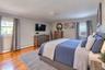 Spacious primary bedroom with en-suite bath, featuring warm hardwood floors and soft gray walls for a serene atmosphere. The room includes a large uph