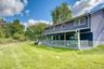 Expansive backyard featuring a large, covered porch that spans the length of the home — perfect for outdoor relaxation or entertaining. The home’s blu