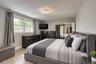 Elegant and spacious bedroom showcasing a modern design with clean lines and neutral tones. The room features a large upholstered bed with coordinated