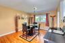 Bright, contemporary dining space with polished hardwood floors and a cozy, open layout. The room centers around a round glass-top table with dark woo