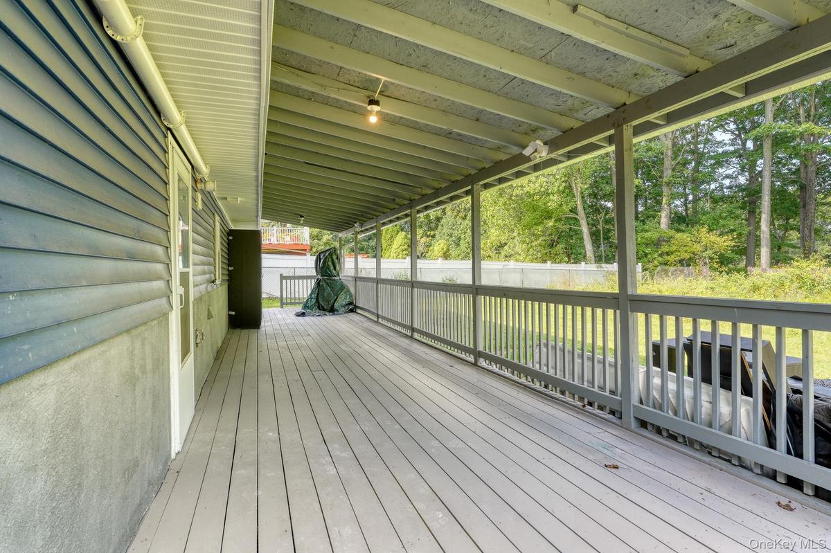 Spacious rear porch featuring a durable wood deck and full overhead coverage for year-round use. The design includes blue siding, white trim, and open