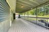 Spacious rear porch featuring a durable wood deck and full overhead coverage for year-round use. The design includes blue siding, white trim, and open