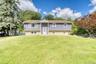 Beautiful split-level home with a modern purple exterior and light brick foundation, set on a spacious, well-manicured lawn. The symmetrical façade fe